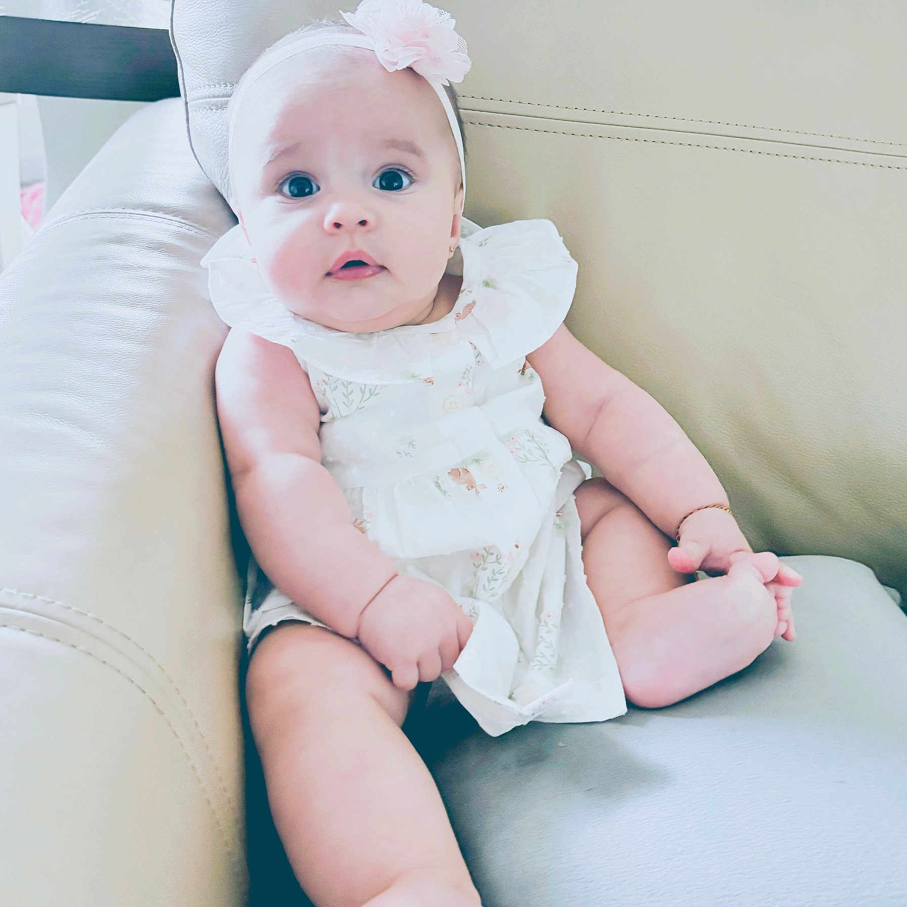 Valentina joined the competition — help win amazing prizes! baby, child, chubby, comfortable, curious, cute, flower, foot, furniture, hand, headband, indoor, infant, leather_couch, person, portrait, sitting, skin, white_dress, young