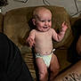 baby, diaper, couch, smiling, happy, infant, tattoo, arm, person, indoor, furniture, skin, hand, face, expression, candid, family, seated, brown, wires
