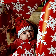 élea participe au concours pour gagner de l'argent avec cette photo : baby, child, face, red_hat, knit_hat, wrapping_paper, snowflake_pattern, holiday, christmas, curious_expression, indoors, cozy, festive, red_clothing, closeup, portrait, cute, winter, soft_light, surprise