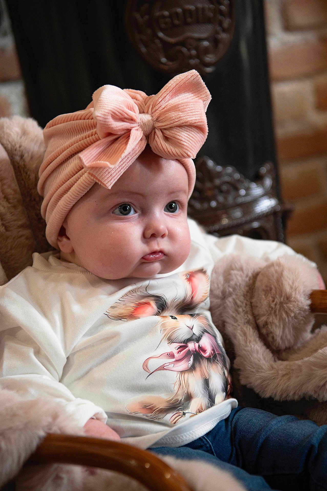 élea a rejoint le concours — aidez-le/la à gagner de superbes lots ! baby, child, infant, pink_bow, headband, cute, shirt, bunny_print, chair, blanket, cozy, indoor, portrait, face, eyes, clothing, comfort, soft, furniture, young