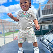 Nazir Anderson joined the competition — help win amazing prizes! toddler, child, smiling, playful, outdoor, clouds, blue_sky, car, sneakers, shorts, tshirt, urban, fence, daylight, standing, person, happy, young_child, fashion, portrait