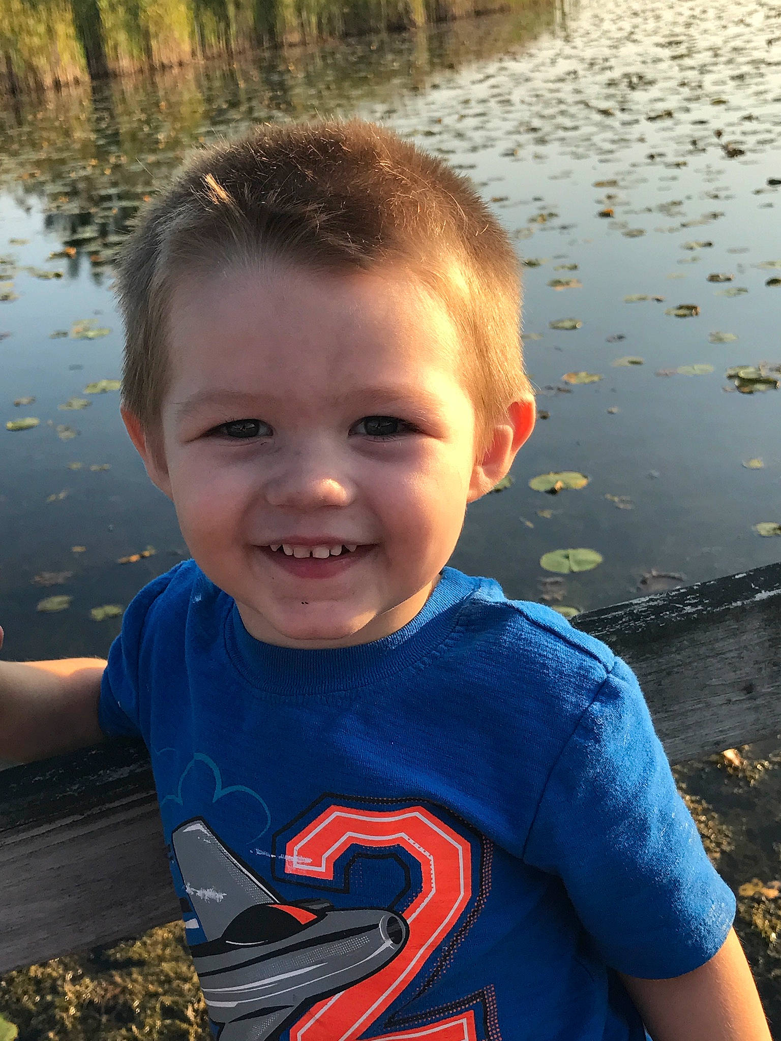 Donald is registered to the contest to win money with this photo: cheek, child, cool, face, facial_expression, fun, happy, joy, lake, male, people, person, play, river, sky, smile, summer, t_shirt, toddler, vacation
