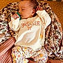 baby, infant, pacifier, blanket, floral_pattern, sweater, winnie_the_pooh, pants, floral_pants, hand, foot, sleeping, crib, striped_background, knit_blanket, cute, child, person, indoors, resting
