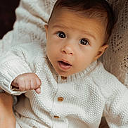 Camille a rejoint le concours — aidez-le/la à gagner de superbes lots ! adult_hand, baby, caring, child, closeup, cute, expression, hand, holding, indoor, infant, knitted_clothing, looking_up, newborn, person, portrait, skin, sweater, warm_light, white