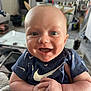 Aiden is registered to the contest to win money with this photo: baby, infant, smiling, happy, blue_shirt, nike_logo, indoor, living_room, person, child, face, closeup, hands, cute, young, expression, toddler, casual, home, portrait