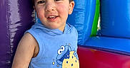 Elias is registered to the contest to win money with this photo: toddler, child, smiling, blue_clothing, sleeveless_shirt, cookie_monster, inflatable, playground, colorful, purple, blue, green, red, happy, sitting, indoor_play, fun, young_child, cute, portrait