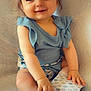 baby, blanket, blue_top, bows, child, cozy, cute, face, hair, happy, heart_sticker, indoor, legs, patterned_paper, person, sitting, skin, small_hands, smiling, toddler