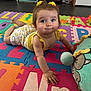 alphabet, baby, child, clothing, colorful, crawling, cute, eyes, face, floor, hair_accessory, hand, indoor, infant, playmat, plush_toy, puzzle_mat, smile, toy, yellow
