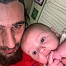 baby, beard, cap, closeup, cuddle, curtains, expression, face, family, hand, headwear, indoor, infant, man, person, photograph, portrait, red_clothing, skin, wall_art