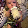 Elias is registered to the contest to win money with this photo: baby, bottle, milk, camo_clothing, infant, hand, nails, person, arm, blanket, cushion, plaid, feeding, indoor, skin, holding, pacifier, comfort, closeup, cute
