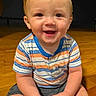 Leo is registered to the contest to win money with this photo: baby, child, smiling, sitting, portrait, indoors, wooden_floor, striped_shirt, blue_clothing, orange_clothing, short_hair, blond_hair, face, hands, water_bottle, plastic_bottle, happy, home, floor, candid_photo