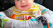 Leo joined the competition — help win amazing prizes! baby, child, infant, smiling, sitting, portrait, face, hands, striped_clothing, activity_seat, baby_toy, colorful, indoor, close_up, happy, playful, fabric, cushion, head, photography