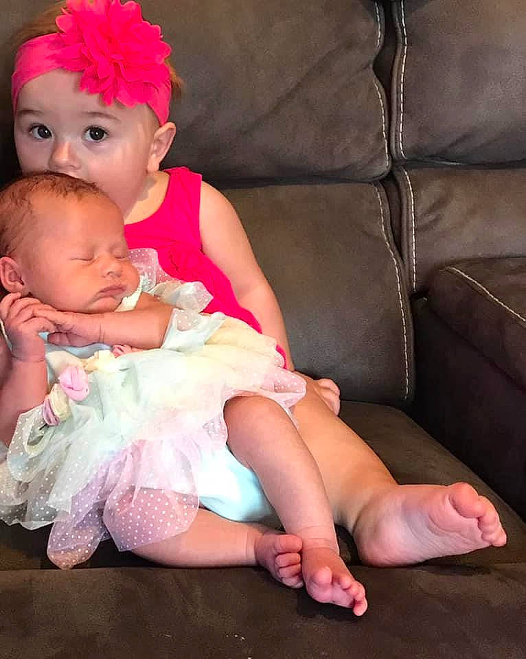 Macey is registered to the contest to win money with this photo: baby, baby_toddler_clothing, comfort, couch, dress, finger, flash_photography, hairstyle, hand, happy, headpiece, headwear, jewellery, knee, lap, leg, person, pink, skin, textile