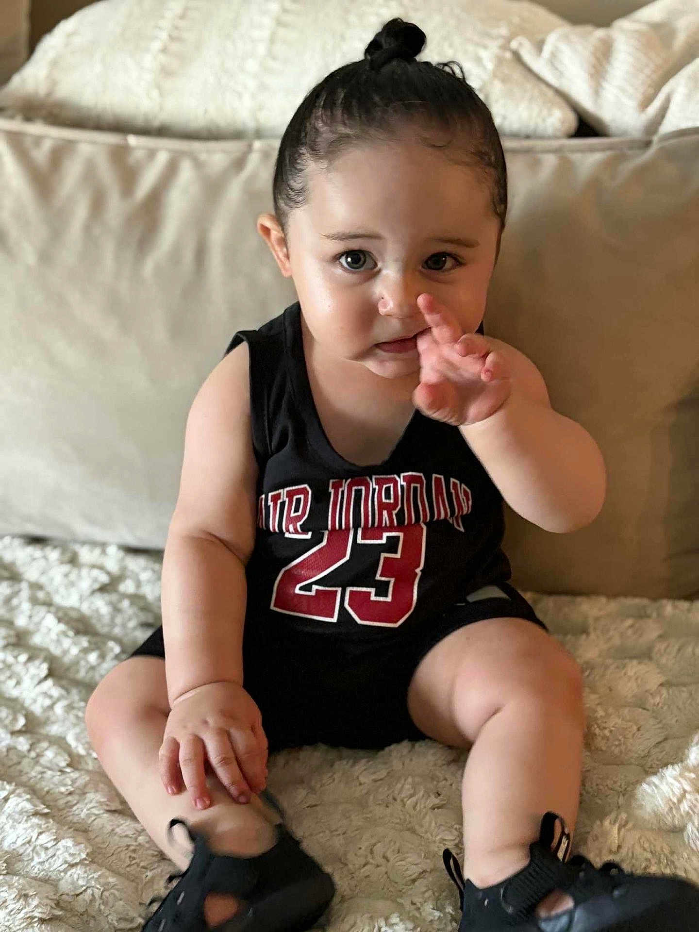 Mahfoud a rejoint le concours — aidez-le/la à gagner de superbes lots ! toddler, child, baby, person, indoors, sitting, black_clothing, air_jordan, sneakers, blanket, pillow, cute, curious, face, hand, footwear, expression, couch, soft_texture, portrait