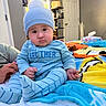 Jr is registered to the contest to win money with this photo: baby, bed, bedroom, blanket, blue_clothing, child, cozy, door, hand, indoor, infant, pajamas, pom_pom, portrait, round_face, serious_expression, shelves, sitting, striped_clothing, winter_hat