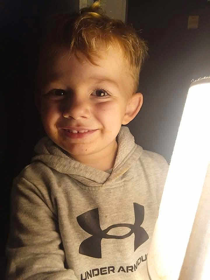 Lyncoln is registered to the contest to win money with this photo: child, smiling, hoodie, blond_hair, under_armour, indoor, portrait, light_source, happy, casual_clothing, young, cute, face, eyes, person, warm_lighting, dark_background, close_up, childhood, expression