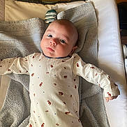 Lancelot participe au concours pour gagner de l'argent avec cette photo : adorable, baby, baby_bed, child, clothing, curious, cute, expression, face, head, indoors, infant, lying_down, newborn, onesie, person, sleepwear, soft, towel, wooden_floor