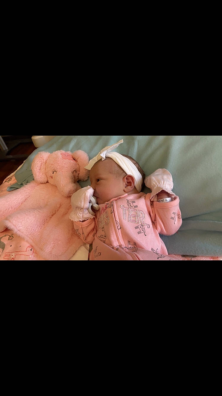 Everly is registered to the contest to win money with this photo: abdomen, baby, baby_sleeping, baby_toddler_clothing, cap, cheek, child, comfort, event, flash_photography, fur, gesture, happy, linens, magenta, peach, person, pink, sitting, sleeve