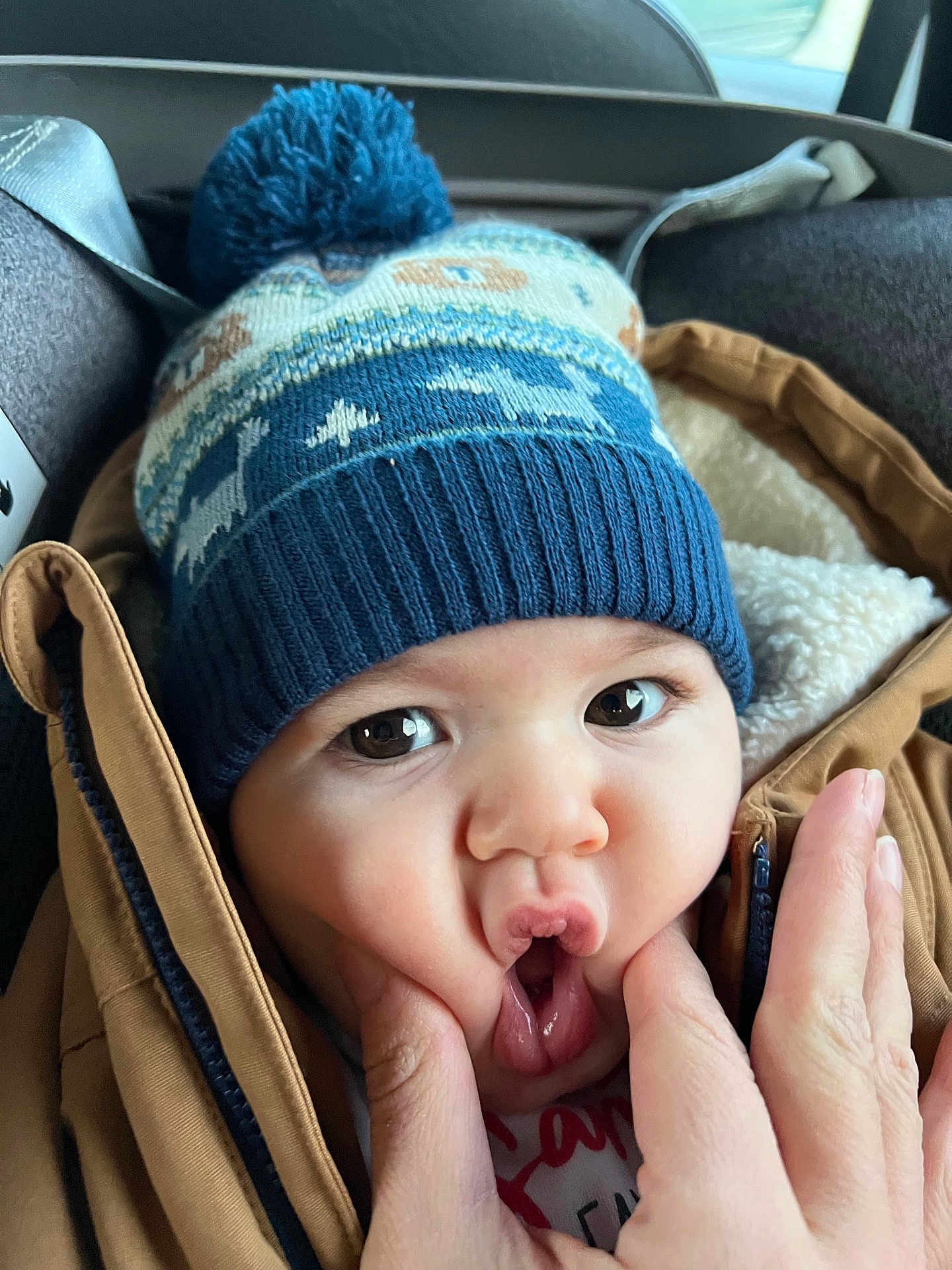 Leo participe au concours pour gagner de l'argent avec cette photo : baby, child, face, hat, winter_hat, pom_pom, jacket, brown_jacket, hand, fingers, expression, funny_face, cute, close_up, indoors, warm_clothing, skin, eyes, mouth, person