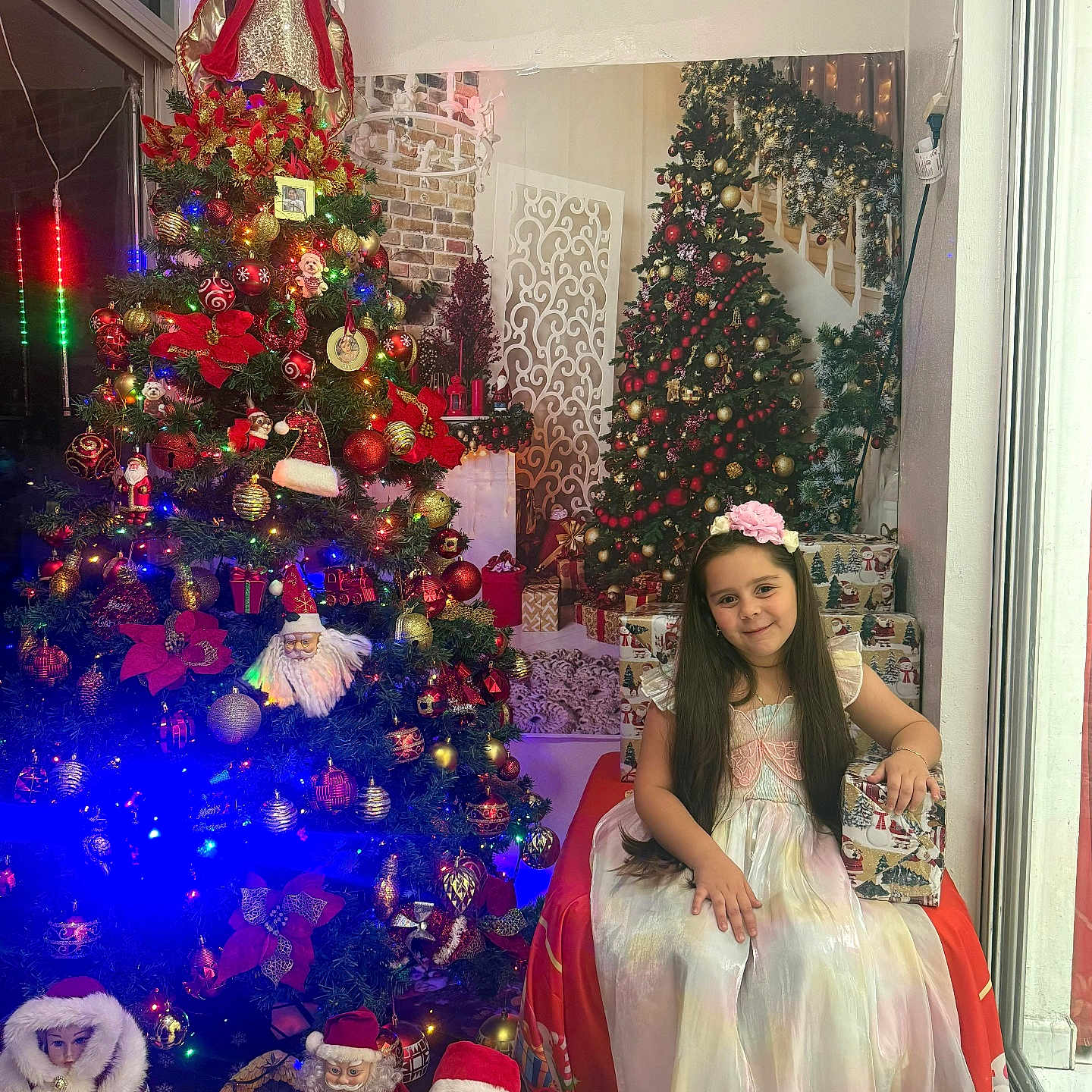 Nathaly Roque joined the competition — help win amazing prizes! celebration, child, christmas_tree, decor, dress, festive, floor, flower_headband, gift_box, girl, holiday, holiday_decorations, indoor, lights, long_hair, ornaments, santa_claus, seasonal, smiling, window