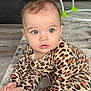 Anya is registered to the contest to win money with this photo: baby, infant, child, blue_eyes, leopard_print, onesie, sitting, carpet, rug, hands, feet, portrait, indoor, home, bouncer, toys, curiosity, cute, expression, hair