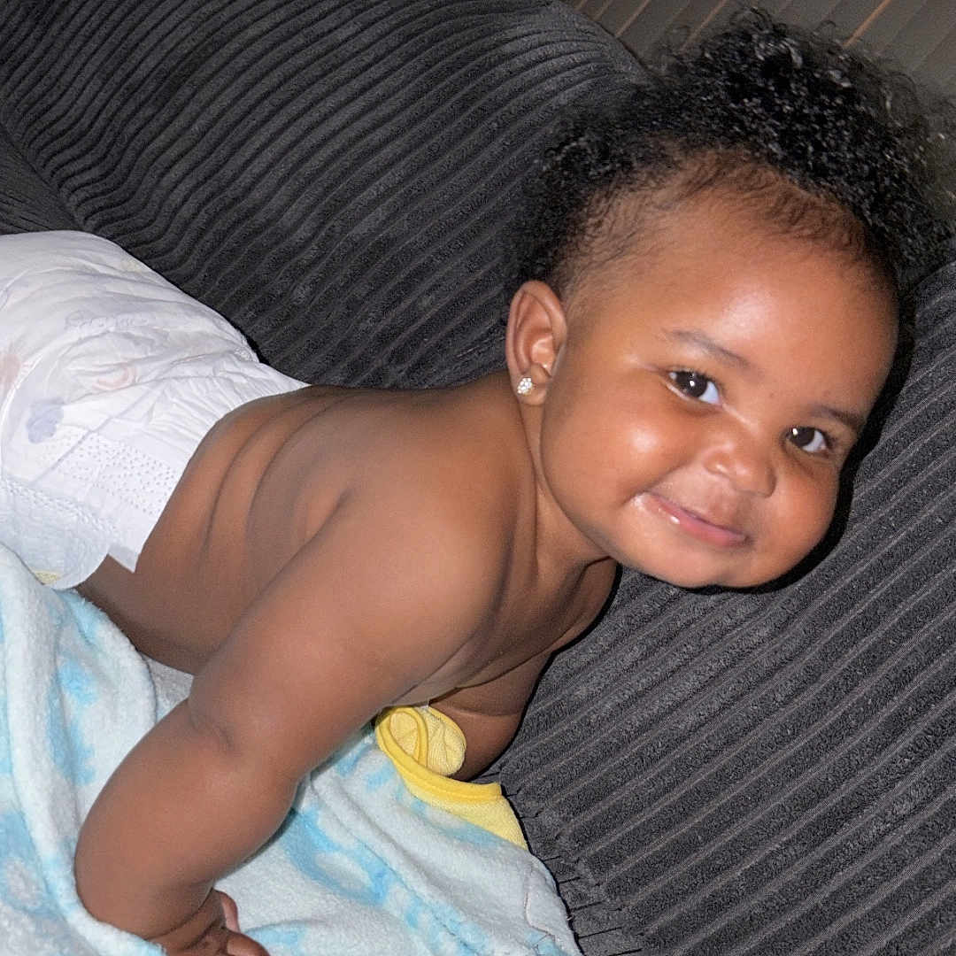 Kaysn Miller joined the competition — help win amazing prizes! baby, child, diaper, smile, curly_hair, couch, blanket, toy, indoor, happy, cute, infant, playful, soft, home, person, face, earrings, skin, toddler