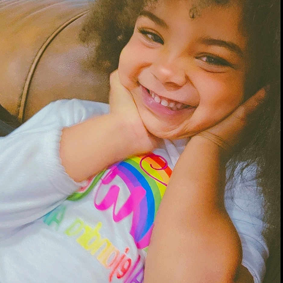 Alejandra is registered to the contest to win money with this photo: bodypart, child, clothing, couch, cushion, face, female, furniture, girl, happy, head, homedecor, laughing, mouth, person, photography, portrait, smile, t_shirt, teeth