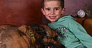 Roc a rejoint le concours — aidez-le/la à gagner de superbes lots ! boy, child, dog, belgian_malinois, pet, portrait, smiling, sitting, couch, leather_sofa, hoodie, jeans, flowers, roses, indoor, studio, brown_dog, green_clothing, animal_companion, happy