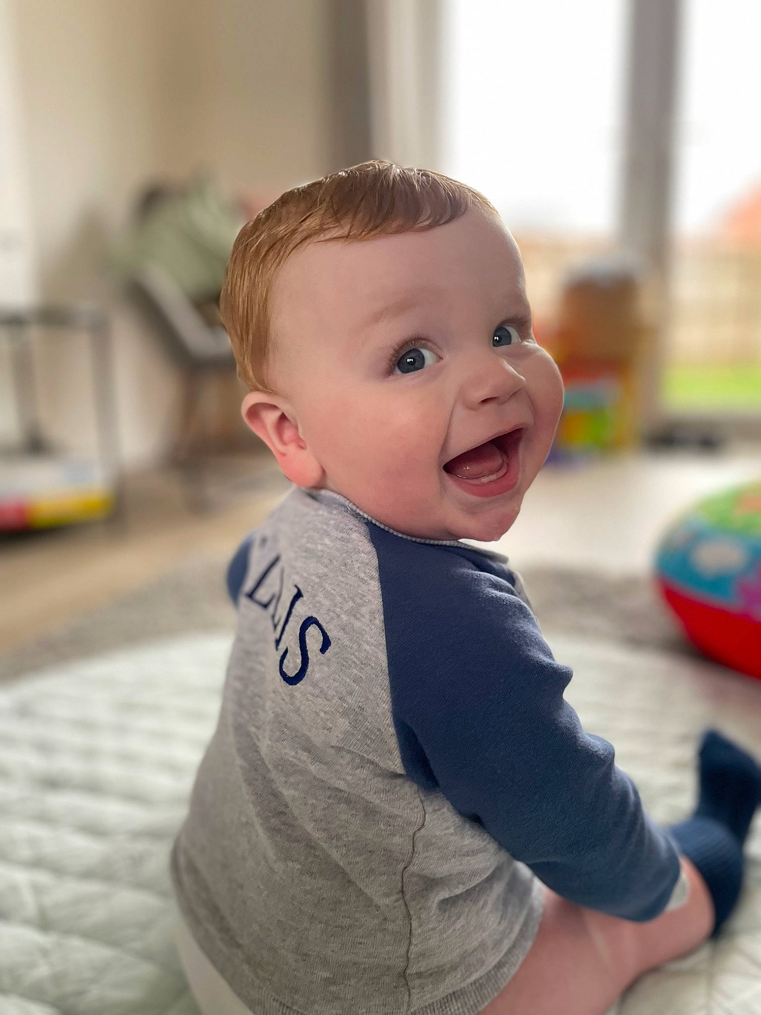 Ellis joined the competition — help win amazing prizes! baby, baby_playing_with_toys, baby_toddler_clothing, blond, cheek, child, eye, floor, flooring, fun, hairstyle, happy, head, leisure, person, sitting, skin, sleeve, smile, t_shirt