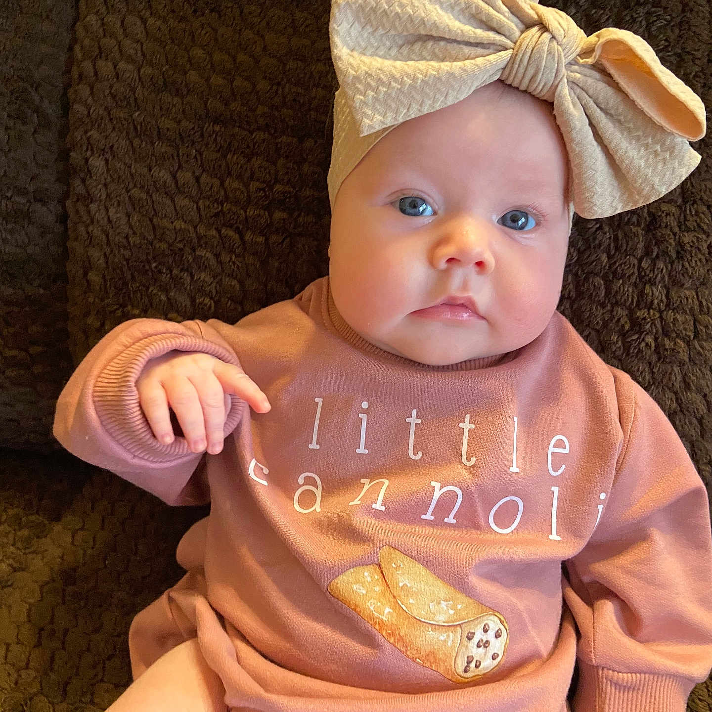 Ava is registered to the contest to win money with this photo: baby, bodypart, bonnet, cap, clothing, couch, face, finger, furniture, hand, hat, head, knitwear, newborn, pants, person, photography, portrait, sitting, t_shirt