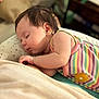 baby, sleeping, infant, pillow, striped_clothing, yellow_flower_patch, star_pattern, closeup, indoors, soft_lighting, peaceful, child, cute, resting, portrait, young_child, skin, hair, hand, cozy