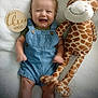 baby, infant, denim_overalls, smiling, plush_giraffe, stuffed_animal, milestone_marker, wooden_plaque, happy, cute, lying_down, soft_blanket, indoor, child, three_months, portrait, toy, young_child, infant_clothing, celebration