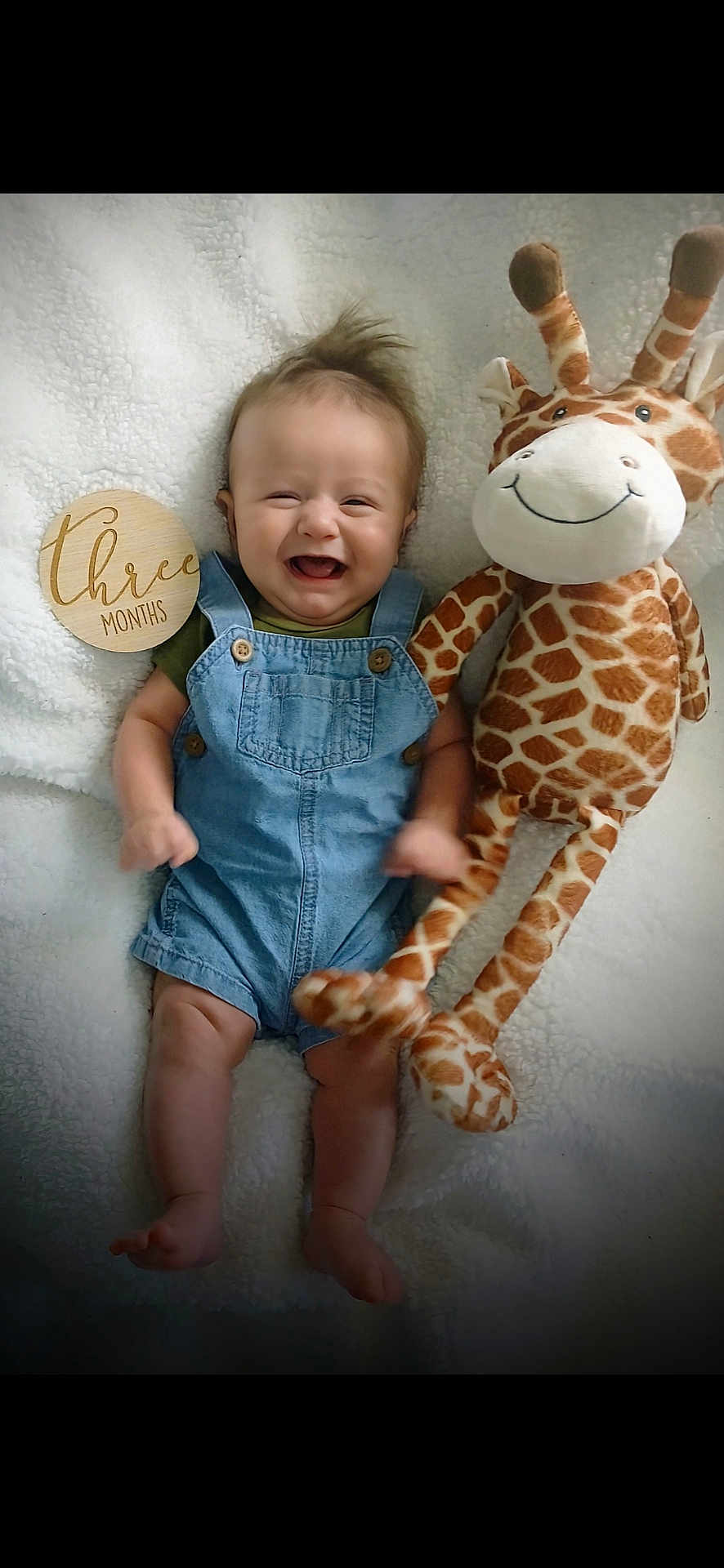 Gabriel joined the competition — help win amazing prizes! baby, infant, denim_overalls, smiling, plush_giraffe, stuffed_animal, milestone_marker, wooden_plaque, happy, cute, lying_down, soft_blanket, indoor, child, three_months, portrait, toy, young_child, infant_clothing, celebration