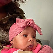 Elaiya is registered to the contest to win money with this photo: apparel, baby, child, closeup, clothing, curly_hair, cute, expression, face, fuzzy_jacket, headband, holding, indoor, infant, person, pink, portrait, soft_texture, warm_clothing, young_child
