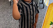 Omari joined the competition — help win amazing prizes! black_shoes, boy, carpet, chair, child, curly_hair, cute, expression, finger_raised, floor, gesture, indoor, person, serious, standing, striped_shirt, table, tablecloth, toddler, young