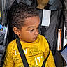 toddler, child, yellow_shirt, stroller, car_seat, seatbelt, curly_hair, plush_toy, dinosaur_toy, looking_down, indoors, casual_clothing, young_child, safety_harness, portrait, cute, baby, seat, child_seat, relaxed