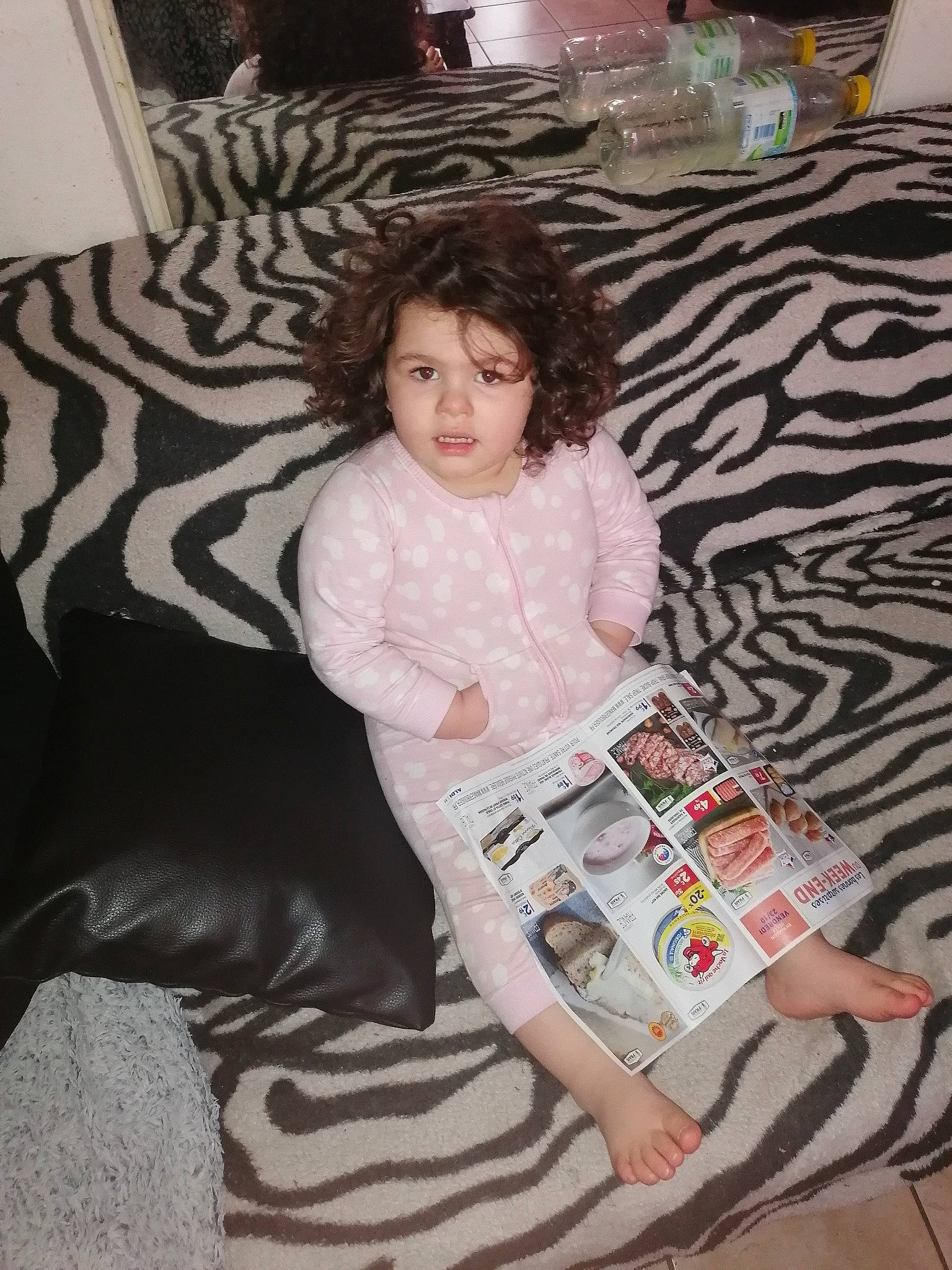Salomé participe au concours pour gagner de l'argent avec cette photo : baby_toddler_clothing, child, comfort, couch, eye, floor, flooring, fun, human_leg, lap, linens, living_room, pattern, person, pillow, room, sitting, sock, thigh, throw_pillow