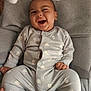 baby, infant, smiling, onesie, sheep_pattern, baby_seat, cushion, hand, happy, child, clothing, indoor, cute, portrait, comfortable, joyful, seatbelt, soft, relaxed, person