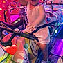 amusement_ride, cartoon, child, colorful, entertainment, excited, family_fun, fun, helmet_headband, indoor, joy, lights, motorbike, playful, smiling, sneakers, toddler, toy, waving, white_clothing