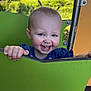 toddler, child, smile, toothy_grin, playground, green_panel, outdoor, park, pigtails, hair_spikes, blue_dress, hands, cheeks, joyful, portrait, metal_structure, sunlight, grass, person, happy
