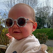 Maddy a rejoint le concours — aidez-le/la à gagner de superbes lots ! baby, child, infant, sunglasses, round_glasses, sweater, smile, portrait, face, ear, hand, outdoor, cloudy_sky, trees, leafless_trees, greenery, bench, accessory, cute, rosy_cheeks