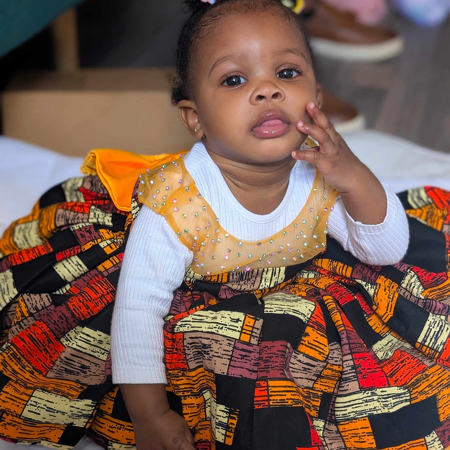 Osasere joined the competition — help win amazing prizes! baby, child, colorful, curly_hair, cute, dress, earrings, expression, eyes, face, floor, hand, indoor, patterned, person, portrait, sitting, toddler, white_shirt, young_child