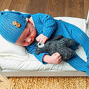 Oliver is registered to the contest to win money with this photo: baby, sleeping, blue_outfit, hat, plush_toy, wooden_bed, white_bed, flooring, woven_rug, cozy, infant, child, cute, indoor, resting, soft_toy, knit_fabric, peaceful, portrait, small_bed