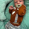 baby, infant, pacifier, bow_tie, suspenders, clothing, cute, portrait, soft_fabric, cushion, lying_down, closeup, child, person, baby_clothes, indoor, expression, head, hand, comfortable