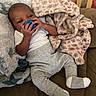 baby, infant, child, portrait, pacifier, smiling, cozy, blanket, pink_blanket, white_blanket, gray_clothing, socks, lying_down, couch, indoor, home, nursery, crib, soft_furnishings, relaxed