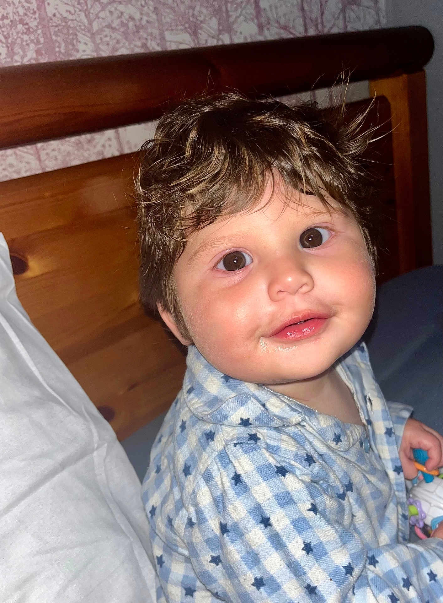 Jax is registered to the contest to win money with this photo: baby, child, portrait, indoor, wood, bed, pillow, clothing, star_pattern, blue, white, face, eyes, hair, smile, cute, infant, person, young, expression