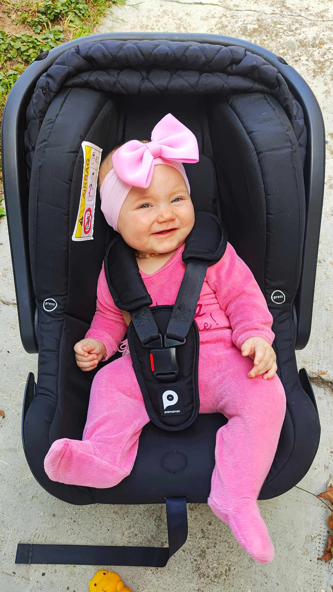 Lexy participe au concours pour gagner de l'argent avec cette photo : baby, pink_outfit, headband, pink_bow, car_seat, black_car_seat, smiling, infant, child, outdoor, concrete_floor, toy, happy, straps, safety_harness, cute, person, footwear, baby_clothing, playful