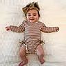 baby, blanket, bow, child, cute, foot, hand, happy, headband, indoors, infant, lying_down, onesie, person, portrait, skin, smiling, striped_clothing, toddler, young
