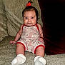 baby, infant, child, sitting, sofa, couch, red_bow, romper, white_socks, cushion, indoor, portrait, cute, chubby_cheeks, happy, comfortable, home, furniture, patterned_clothing, smiling