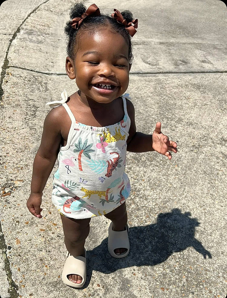 Gianna is registered to the contest to win money with this photo: asphalt, baby, baby_toddler_clothing, child, eye, face, finger, fun, grass, hairstyle, hand, happy, human_leg, person, pink, skin, sleeve, smile, soil, t_shirt